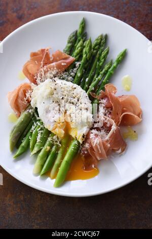 Uova Benedetto con parmigiano, asparagi verdi e prosciutto di Parma. Foto Stock