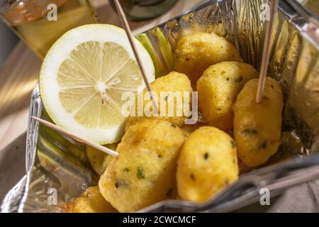 Street food siciliano, crocchette di patate chiamate 'crocchè' serviti in un contenitore di alluminio con limone Foto Stock