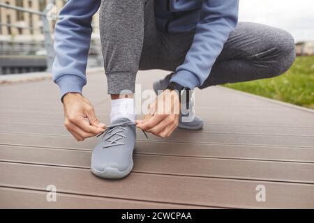 Primo piano dell'atleta che lega le sue sneakers prima di fare jogging all'aperto Foto Stock