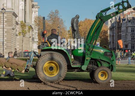 Paesaggisti visto al lavoro con macchinari pesanti e la posa di un nuovo prato sul giardino di Parliament Square. Foto Stock