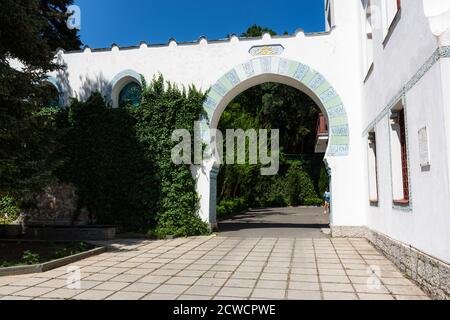Palazzo Dulber Yalta Crimea 16 giugno 2019. Vista dell'arco vicino all'edificio principale. Edificio bianco neve con decor di colore blu Orientale. Centro benessere a Orie Foto Stock
