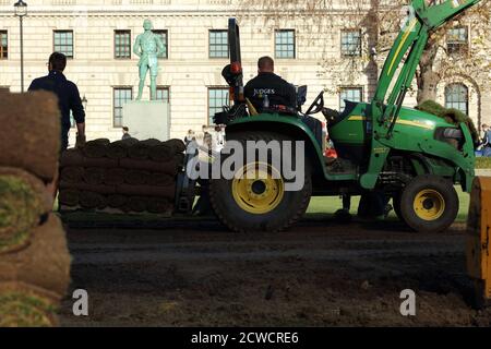 Paesaggisti visto al lavoro con macchinari pesanti e la posa di un nuovo prato sul giardino di Parliament Square. Foto Stock