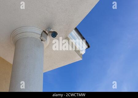 Telecamera di sorveglianza cctv (televisione a circuito chiuso) installata sul tetto della casa privata su sfondo blu per la protezione contro il crimine. Vi. Inferiore Foto Stock