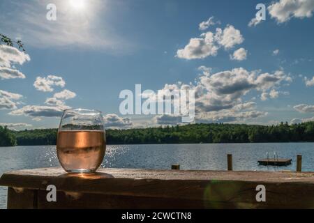 Primo piano di un bicchiere di vino con vino rosato e bellissimo lago in background Foto Stock