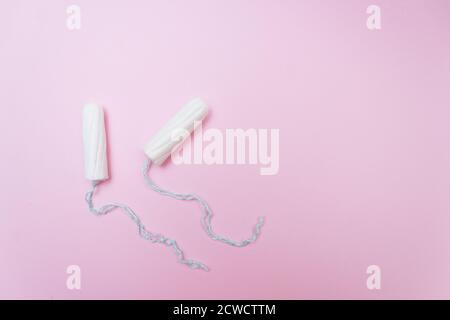 Concetto di periodo mestruale. Protezione igienica per le donne. Tamponi in cotone su sfondo rosa. Vista dall'alto, disposizione piatta. Foto Stock