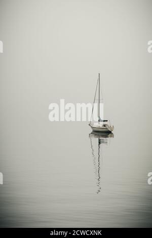 Puget Sound, Washington, settembre 20,2020, barca a vela ancorata al largo della costa nella nebbia mattutina Foto Stock