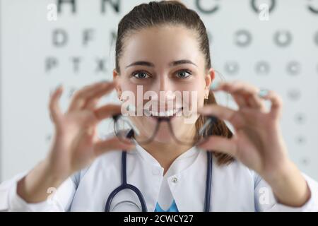 Donna oftalmologo dà occhiali per il montaggio sullo sfondo del tavolo per la misurazione della visione
