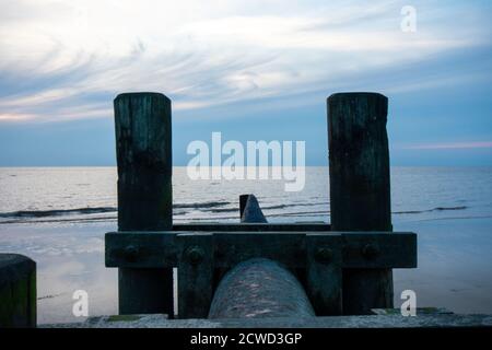 Un tubo grande con poli di legno su ogni lato che si attacca Fuori nell'oceano Foto Stock