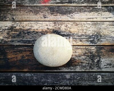 Primo piano di un vecchio cannone di pietra sulla superficie di legno Foto Stock