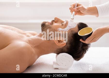 Uomo che ottiene il trattamento del viso al salone di bellezza Foto Stock