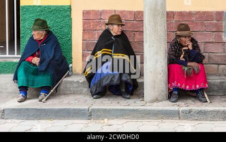 Canar, Ecuador - Luglio 12, 2015 - Tre anziani Canar donne siedono sul marciapiede, a guardare il mondo che passa da Foto Stock