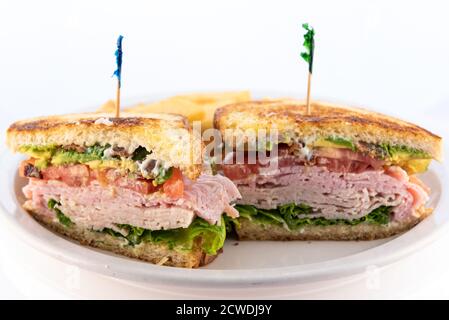 Pasto generoso con una sostanziosa carne a strati, avocado, pancetta, sandwich accatastati sul piatto. Foto Stock