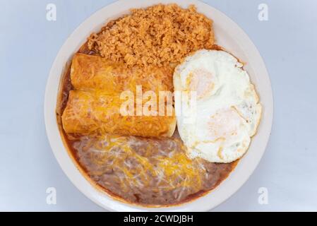 Vista dall'alto di un generoso pasto che serve un sostanzioso paio di enchiladas per la colazione combinati con fagioli, riso e uova fritti. Foto Stock