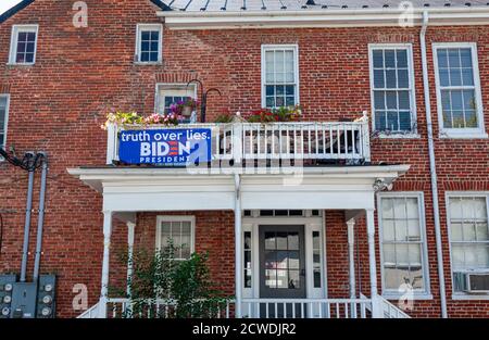 Berryville, VA, USA 09/27/2020: Un Biden blu per la bandiera del presidente è attaccato alle ringhiere di legno del balcone del secondo piano ad un ho di mattone vintage Foto Stock