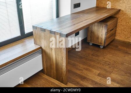 Arredamento moderno. Console in legno massello con giunzione a scatola sullo sfondo della finestra Foto Stock