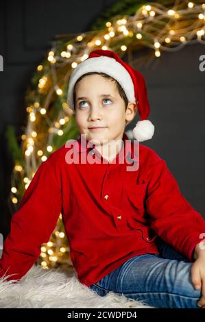 Allegro ragazzino che gioca a casa. Ragazzo felice nel cappello rosso di Santa Foto Stock