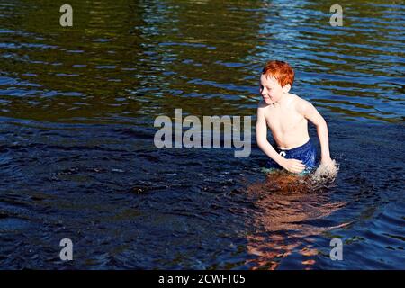Umea, Norrland Svezia - 28 giugno 2020: Il giovane ragazzo gioca in acqua in modo che schizzi ovunque Foto Stock