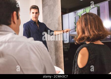 Tre giovani architetti discutono insieme all'interno di una sala conferenze il nuovo concetto di interior design per una presentazione del marchio. I giovani imprenditori lavorano Foto Stock