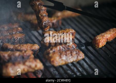 Immagine della profondità di campo poco profonda (fuoco selettivo) con mici tradizionali rumeni (mitigei), involtini di carne macinati alla griglia a forma cilindrica sul barbecue Foto Stock