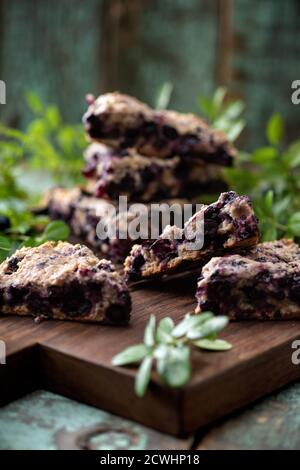 Focaccine di mirtillo su tavola di quercia con foglie di mirtillo su vecchio fuoco selettivo sfondo legno verniciato Foto Stock