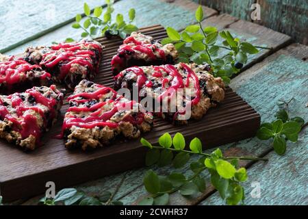 Focaccine tagliate al mirtillo su tavola di quercia con foglie di mirtillo con vecchio legno dipinto primo piano Foto Stock