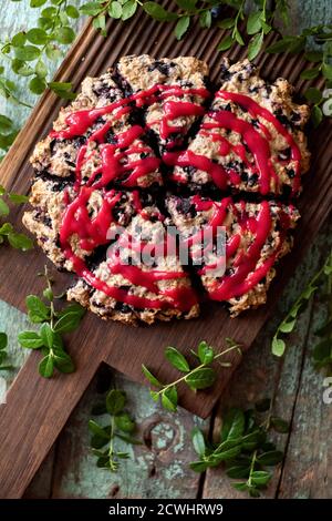 Focaccine tagliate al mirtillo su tavola di quercia con foglie di mirtillo in testa visualizza Foto Stock