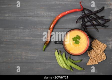 Tazza di fagioli e piselli schiacciati di zuppa su sfondo di legno scuro con cracker di cereali. Inserire uno spazio per la copia Foto Stock