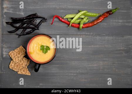 Una tazza di fagioli e piselli schiacciati di zuppa su sfondo di legno scuro con cracker di cereali. Inserire uno spazio per la copia Foto Stock