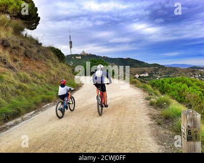 Padre e figlio che cavalcano la loro moto nel tempo libero. Carretera de les Aigües, Parc de Collserola, Barcellona, Catalogna, Spagna. Foto Stock