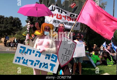 GERUSALEMME, ISRAELE - 29 SETTEMBRE: Un manifestante vestito da un busty costume cartoon tiene un cartello che recita "la democrazia era qui" di fronte al parlamento israeliano durante una manifestazione sulla legislazione che limita le proteste in un blocco a livello nazionale volto a contenere la pandemia del coronavirus il 29 settembre 2020 a Gerusalemme, Israele. Il parlamento israeliano ha approvato modifiche alla legge del Coronavirus che limiterebbero le proteste contro il primo ministro Benjamin Netanyahu chiedendo le sue dimissioni per la sua accusa di corruzione e la gestione della pandemia del coronavirus. Foto Stock