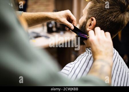 Felice giovane bell'uomo che visita hairstylist nel salone del barbiere Foto Stock