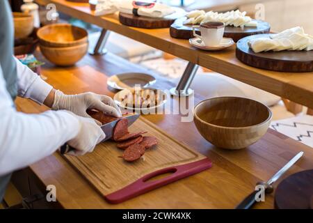 Affettare la salsiccia per le mani Foto Stock