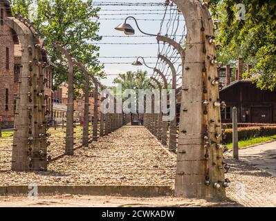 Oświęcim, Polonia - 05 Giugno 2019: recinto elettrico con il filo spinato e mattone carcere edifici al Campo di Concentramento di Auschwitz-Birkenau in Oświęcim, Foto Stock