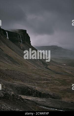 Il paesaggio di montagna nuvoloso scuro e arido drammatico a bassa nuvola dei Westfjords nel Nord Ovest dell'Islanda. Foto Stock