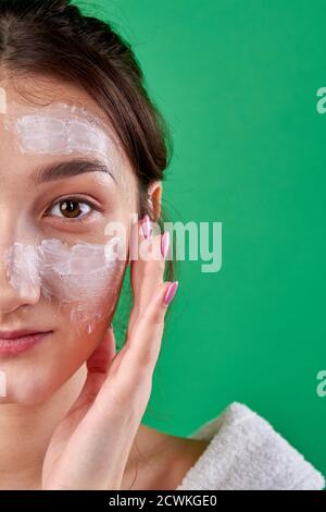 Primo piano la crema di applicazione della donna sulla sua faccia. Foto Stock