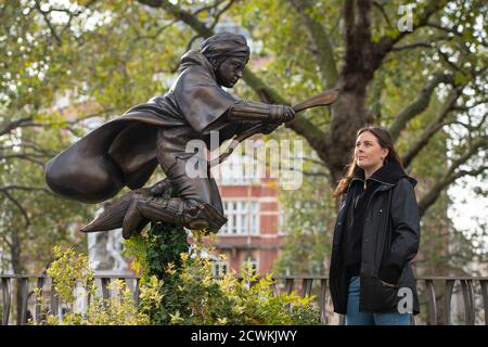 Una donna guarda la nuova statua di Harry Potter, in Leicester Square, Londra, raffigurante Daniel Radcliffe nel suo ruolo come il famoso mago in una scena del primo film, Harry Potter e la pietra del filosofo. Foto Stock