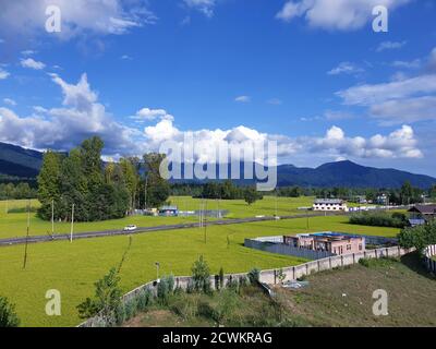 Destinazione Vista del cielo blu nuvoloso bei villaggi e risaie di abitanti del villaggio negli stati indiani. Colture di colore verde e giallo dorato in India Foto Stock