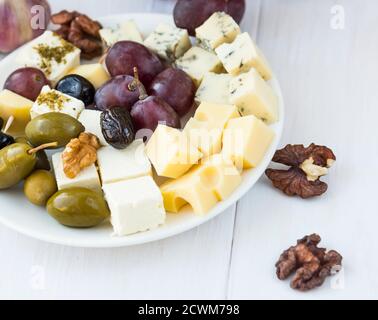 Piatto di formaggi con diversi tipi di formaggio, uva, olive e noci Foto Stock