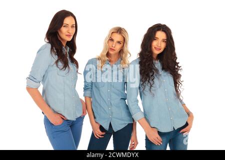 tre modelli di moda in blu jeans vestiti in piedi su bianco sfondo Foto Stock