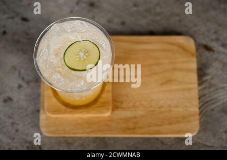 Un bicchiere di plastica di limone di miele ghiacciato con acqua di spaving è su un piatto di legno, fuoco selettivo della vista dall'alto Foto Stock