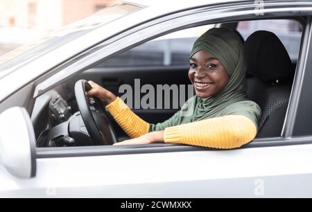 Concetto di assicurazione auto. Donna musulmana africana sorridente seduto in un veicolo moderno Foto Stock