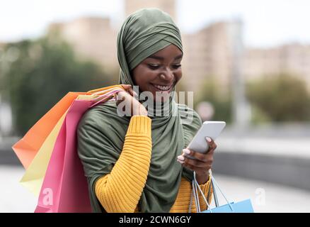 App. Taxi Black Muslim Woman Ordering Cab Outdoors tramite applicazione su smartphone Foto Stock