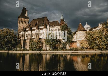 Enlightened Vajdahunyad Castle, the agriculture museum in Budapest in Hungary, with the reflection on the surface of the lake during the autumn day Foto Stock