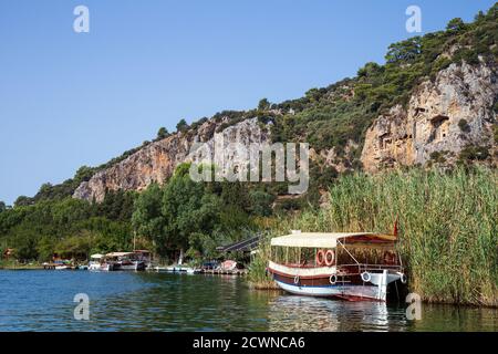 Dalyan, Mugla / Turchia - 09/26/2020: Vista panoramica sulle tombe di roccia licana, e gite in barca con i turisti sul fiume Dalyan in Turchia. Foto Stock
