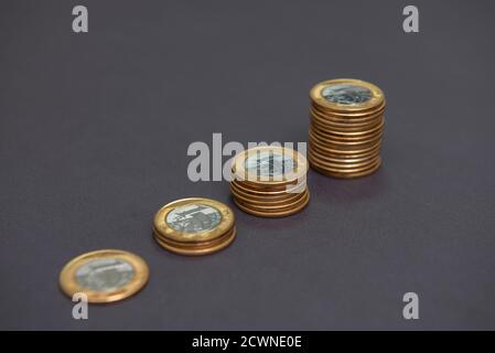 Pile di monete d'oro e d'argento (1 reale) come in un grafico crescente, che rappresentano l'aumento o la caduta su bacground nero. Concetto di economia. Spazio di copia. Selettivo Foto Stock