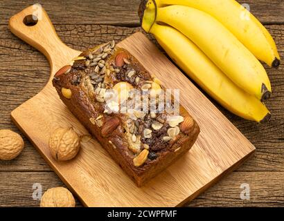 Pane di banana su piastra di legno con banana su sfondo di tavola di legno. Foto Stock