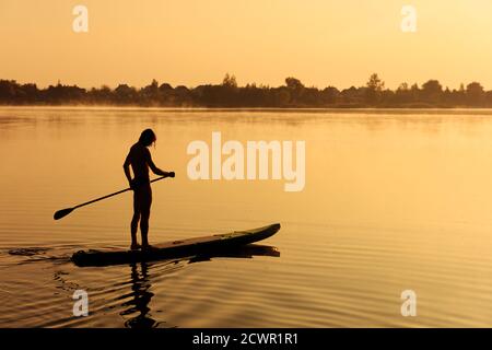 Uomo sportivo forte che usa la pala per galleggiare su sup board Foto Stock