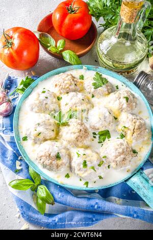 Polpette di pollo bianche e cremose fatte in casa. Polpette classiche svedesi con salsa cremosa di formaggio, con parmigiano e prezzemolo, in padella sullo ston grigio Foto Stock