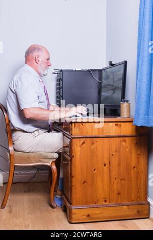 Gentleman di 70 che lavora sul suo computer desktop. Foto Stock