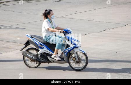 SAMUT PRAKAN, THAILANDIA, 23 2020 LUGLIO, donna con maschera faccia corre una moto Foto Stock